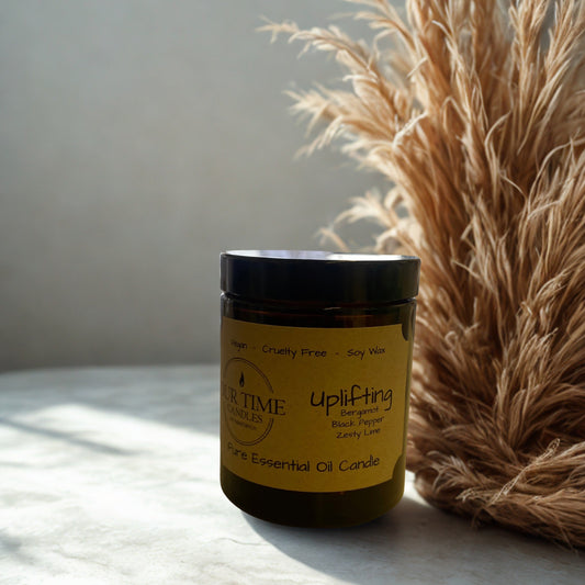 Candle jar labeled 'Uplifting' with a decorative plant on a light surface